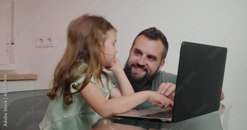 Father helps little daughter do homework on laptop at home Father helps little daughter do homework on laptop at home