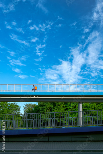 Bicycle bridge surrounded by trees. Bicycle path, scooter on blue sky. Food delivery