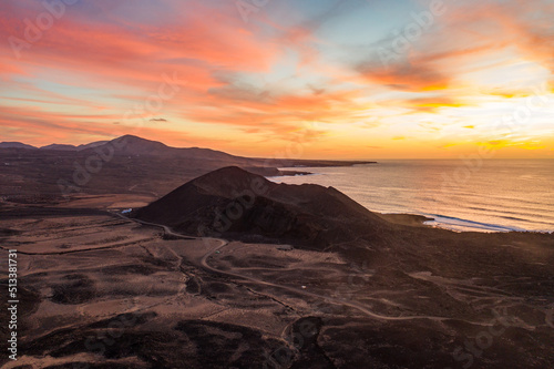 aerial view of volcanic landscape with volcano at coast during sunset 