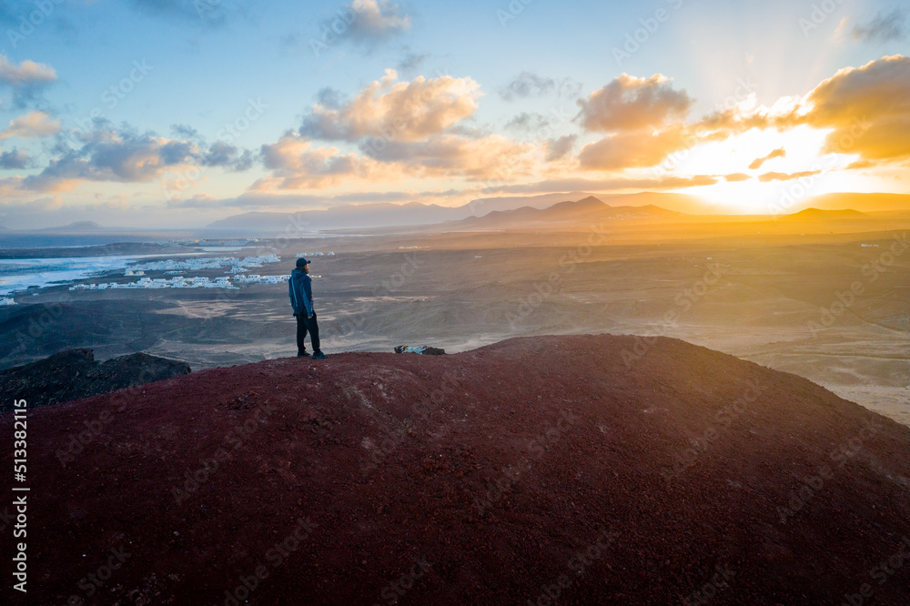 Fototapeta premium man standing on volcano enyoing lanzarote landscape during sunrise