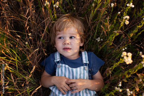 happy and smiling little boy enjoying spring in the meadow lying on the grass.