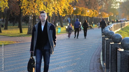 Stylish, handsome young Caucasian man walks along the embankment after work. A confident and successful guy walks by the river. Slow motion. High quality FullHD footage
