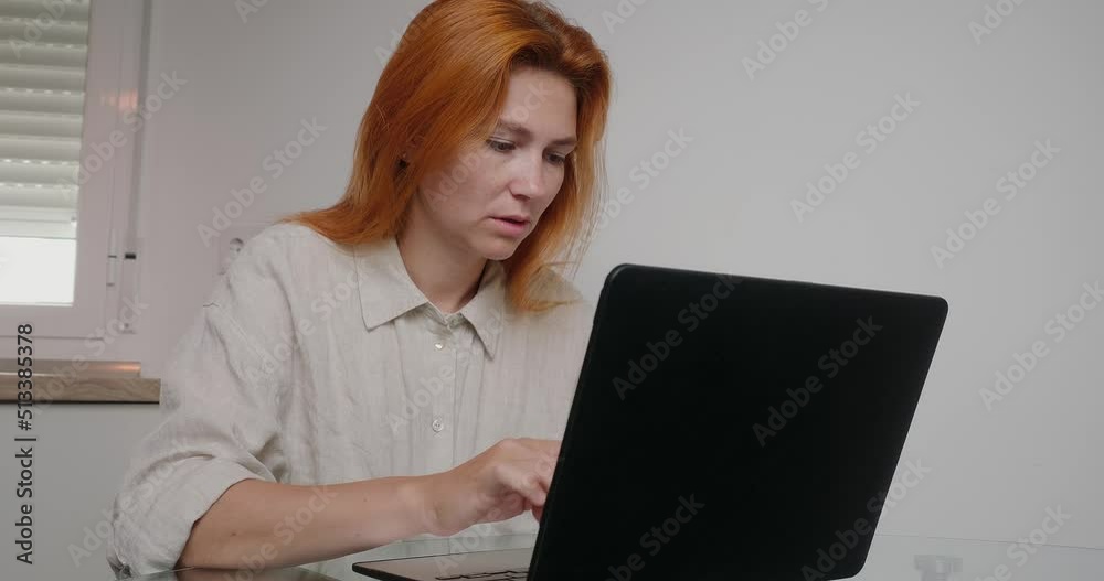 Redhead lady works on laptop searches information in laptop
