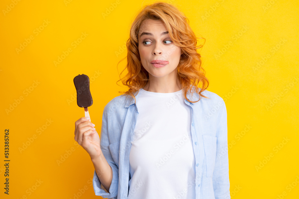 Young woman eat ice creams with chocolate glaze on yellow background. Funny redhead woman with ice cream. Licking lips. Young woman eat ice creams with chocolate glaze on yellow background. Funny redhead woman with ice cream. Licking lips.