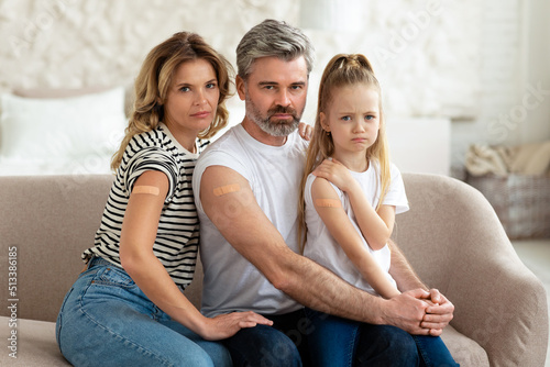 Displeased Vaccinated Family Showing Arms With Adhesive Bandage At Home