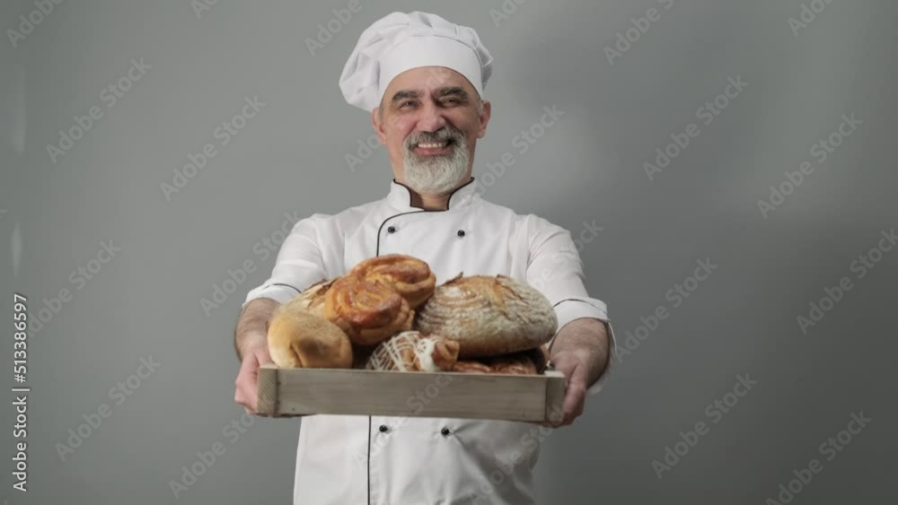 Professional baker offering freshly baked bread. Chef-cooker in a chef's hat and jacket. Senior baker man wearing a chef's outfit. Character kitchener, pastry chef for advertising.