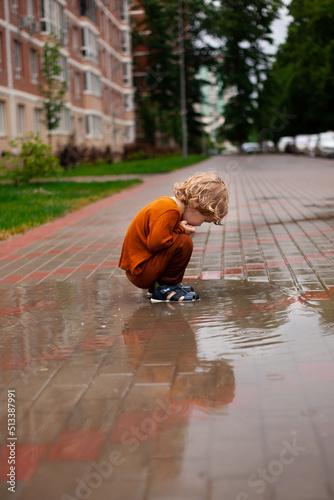 a little boy runs and jumps in the puddles during the summer rain.Childhood.