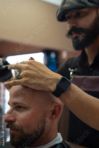 Barber shop, barber shaving his client, selective focus.