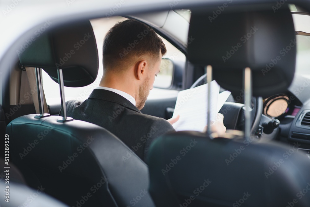 Always in a hurry. Handsome young man in full suit smiling while driving a car.