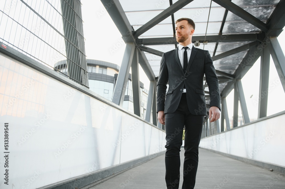 Stockbroker near the office. A successful and advanced handsome business man in a suit looks up in front of him standing on the background of concrete steps.