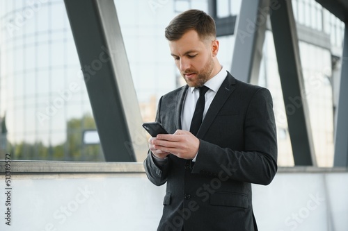 Confident young businessman using cell phone in the city.