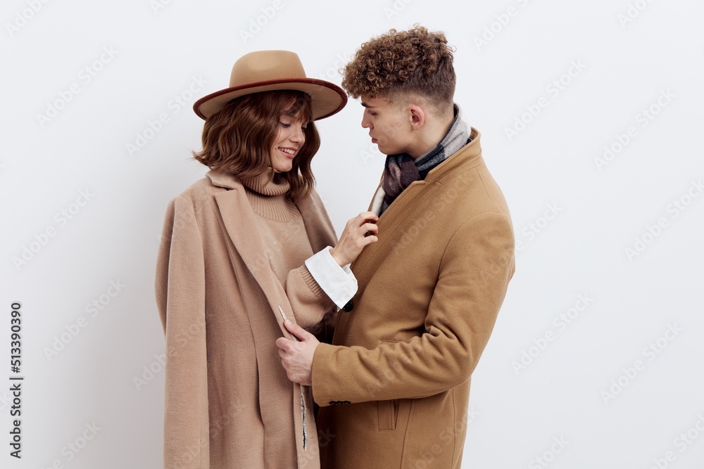 a sweet, beautiful, loving couple stands on a white background in stylish autumn clothes, a woman has a hat on her head, and she gently snuggles up to a man looking at him a sweet, beautiful, loving couple stands on a white background in stylish autumn clothes, a woman has a hat on her head, and she gently snuggles up to a man looking at him