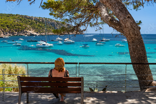 Woman sitting on a promenade bench with a view to the bay of Sant Elm - 1714 photo