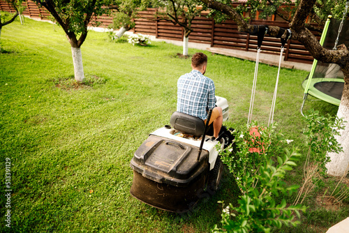 Portrait of happy worker using lawn tractor for cutting grass photo
