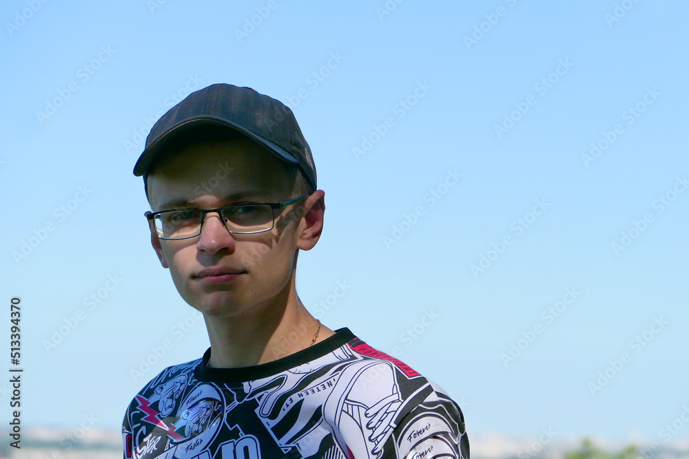 Generation Z. Portrait of a young man of European appearance in glasses and a baseball cap, in the summer on the street. Generation Z. Portrait of a young man of European appearance in glasses and a baseball cap, in the summer on the street.
