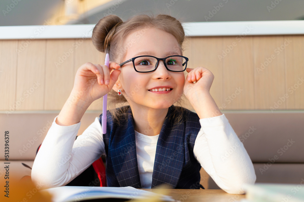 little funny stylish girl in glasses doing homework, studing at school. fashionable child with poor eyesight. concept of training, optometrist, ophthalmologist, childhood health. smart kid. little funny stylish girl in glasses doing homework, studing at school. fashionable child with poor eyesight. concept of training, optometrist, ophthalmologist, childhood health. smart kid.
