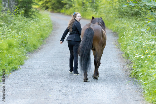 Icelandic horse on gravel road with young woman. Shot in the evening middle of the summer in Finland