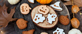 Homemade halloween holiday treats for kids. Gingerbread cookies on wooden board, decorated with pumpkins and autumn leaves. Top view Banner