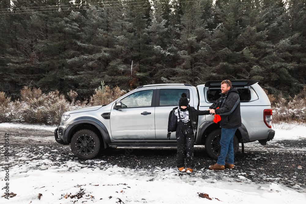 Father and son removing snow gear at vehicle after fun times in the snow Father and son removing snow gear at vehicle after fun times in the snow