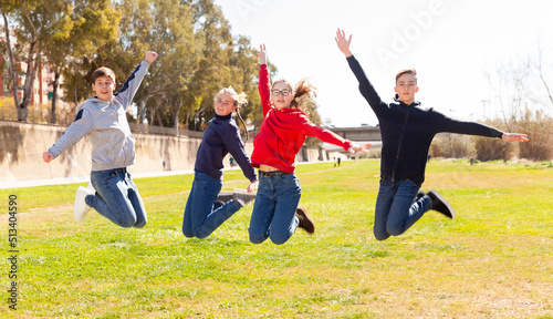 Friendly teenagers jumping together in park on spring