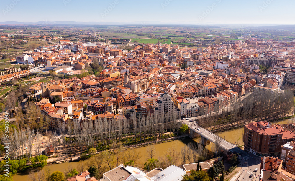 Picturesque aerial view of Spanish city of Aranda de Duero with terracotta tiled roofs of residential buildings on banks of river in spring