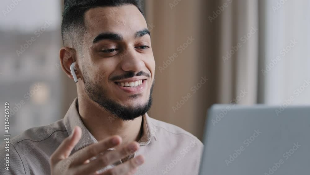 Positive hispanic young man guy male teacher wear wireless earphones look at laptop screen talk at webcam call video chat consult client online provide remote job interview use internet at home office Positive hispanic young man guy male teacher wear wireless earphones look at laptop screen talk at webcam call video chat consult client online provide remote job interview use internet at home office