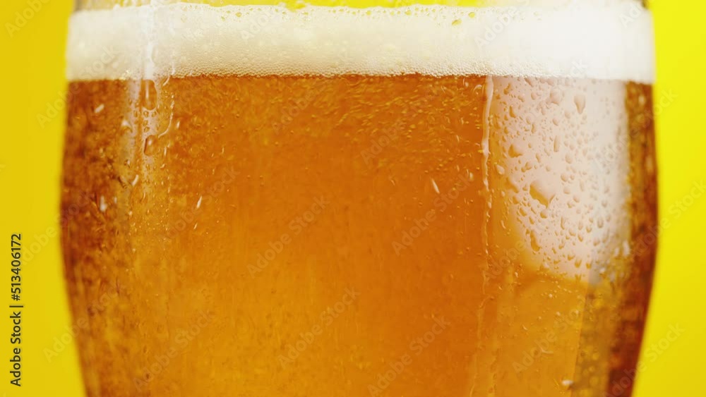 Foamy beer in glass close-up. Alcohol golden beer drink in mug. Fresh pale ale on yellow background. Foamy beer in glass close-up. Alcohol golden beer drink in mug. Fresh pale ale on yellow background.