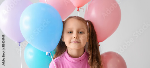 Cute little girl with balloons on grey background