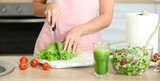 Young woman making fresh salad in kitchen