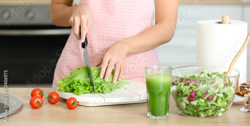 Young woman making fresh salad in kitchen