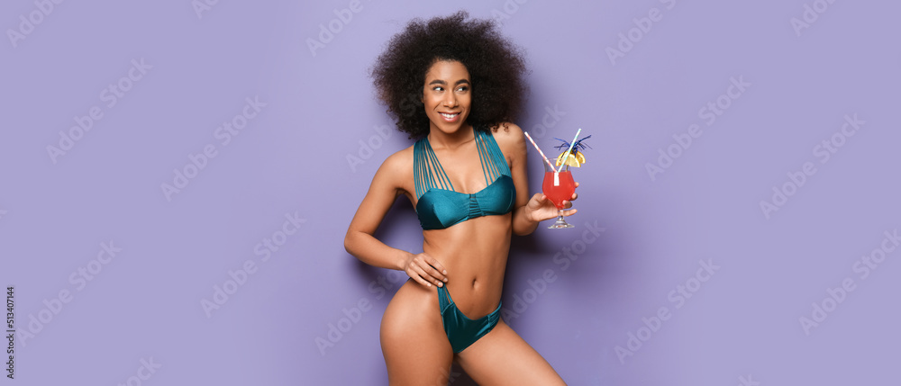 Naklejka premium Beautiful African-American woman in bikini and with cocktail on lilac background
