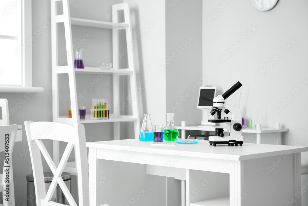 Modern workplace with chemical glassware and microscope in medical laboratory