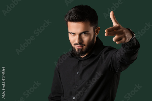Bearded man pointing fingers gun gesture on color background