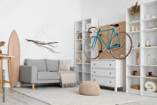 Interior of modern living room with bicycle, surfboard and chest of drawers