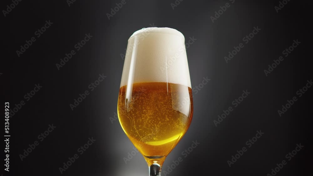Foamy beer in glass close-up. Alcohol golden beer drink in mug. Fresh pale ale on black background. 