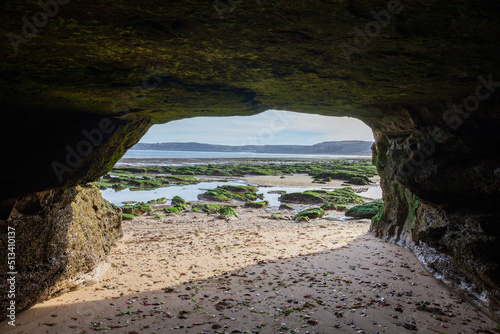 View from the cave to the sandy beach, huge stones with algae during the low tide of the Atlantic Ocean, Valdes Peninsula, Puerto Piramides, Patagonia, Argentina