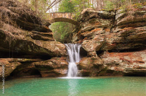Cascading waterfall flowing under arch bridge in Hocking Hills State Park, Ohio. 