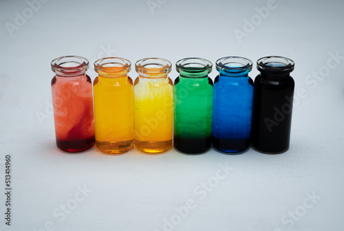 hilera de botellitas con agua coloreada multicolor, arcoiris con fondo blanco 