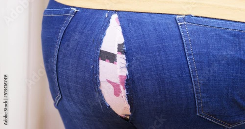 Fat person tried to sit down or bend over, but the jeans were torn at the seam and pink underpants appeared under them, view from back, close up. Wrong size of pants