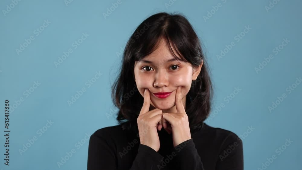 Asian woman clowning herself over blue background Asian woman clowning herself over blue background
