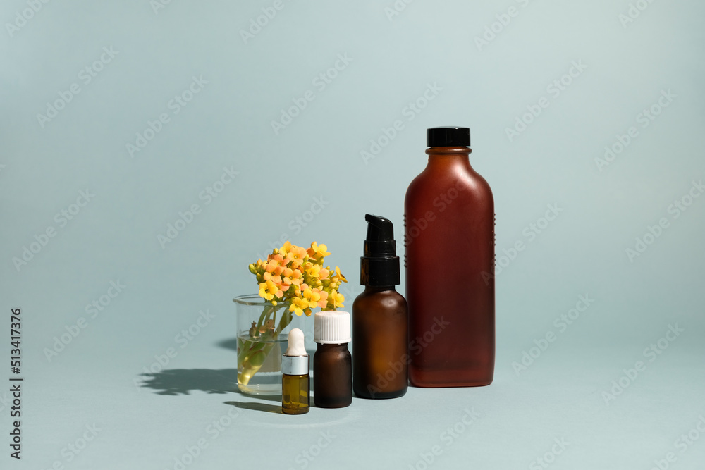 The set of amber glass bottles with flowers on blue background. The set of amber glass bottles with flowers on blue background.