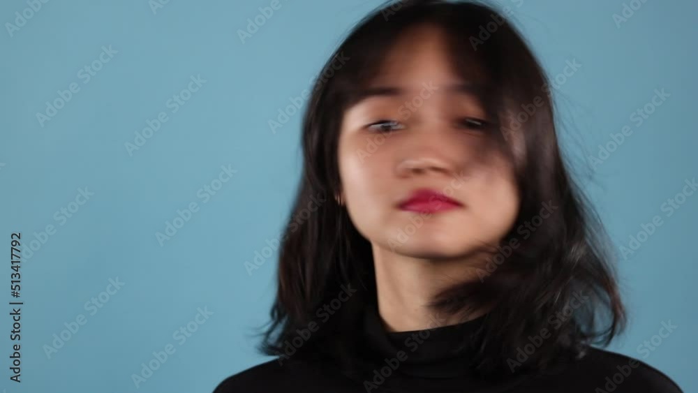 Asian woman stressing about herself over blue background Asian woman stressing about herself over blue background