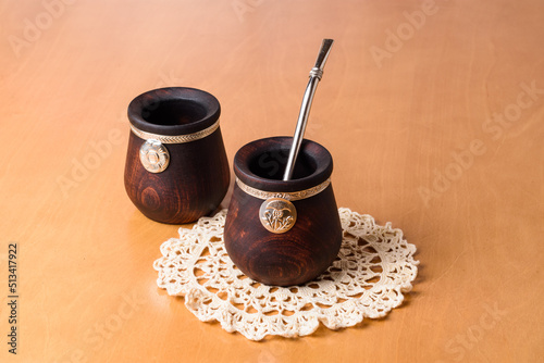 Tazas de madera tallada y plata cincelada para beber infusión de yerba mate, sobre pequeño mantel tejidos photo