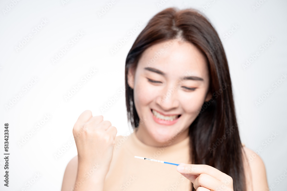 Happy asian woman shows a positive ovulation test. The concept of female fertility and high luteinizing hormone. The right time to conceive a child. infertility Concept. Happy asian woman shows a positive ovulation test. The concept of female fertility and high luteinizing hormone. The right time to conceive a child. infertility Concept.