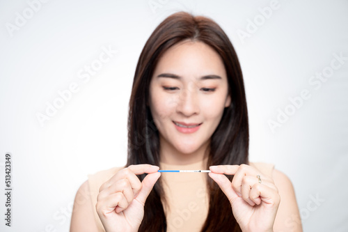 Happy asian woman shows a positive ovulation test. The concept of female fertility and high luteinizing hormone. The right time to conceive a child. infertility Concept.