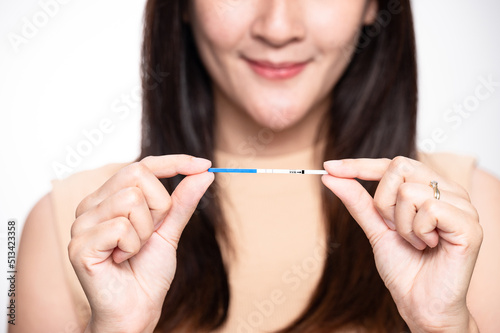 Happy asian woman shows a positive ovulation test. The concept of female fertility and high luteinizing hormone. The right time to conceive a child. infertility Concept.