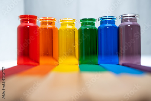 hilera de botellitas con agua coloreada multicolor, arcoiris con fondo blanco y palitos de madera en la base photo