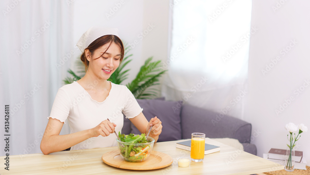 Lifestyle in living room concept, Young Asian woman mixing vegetable salad in bowl for breakfast Lifestyle in living room concept, Young Asian woman mixing vegetable salad in bowl for breakfast
