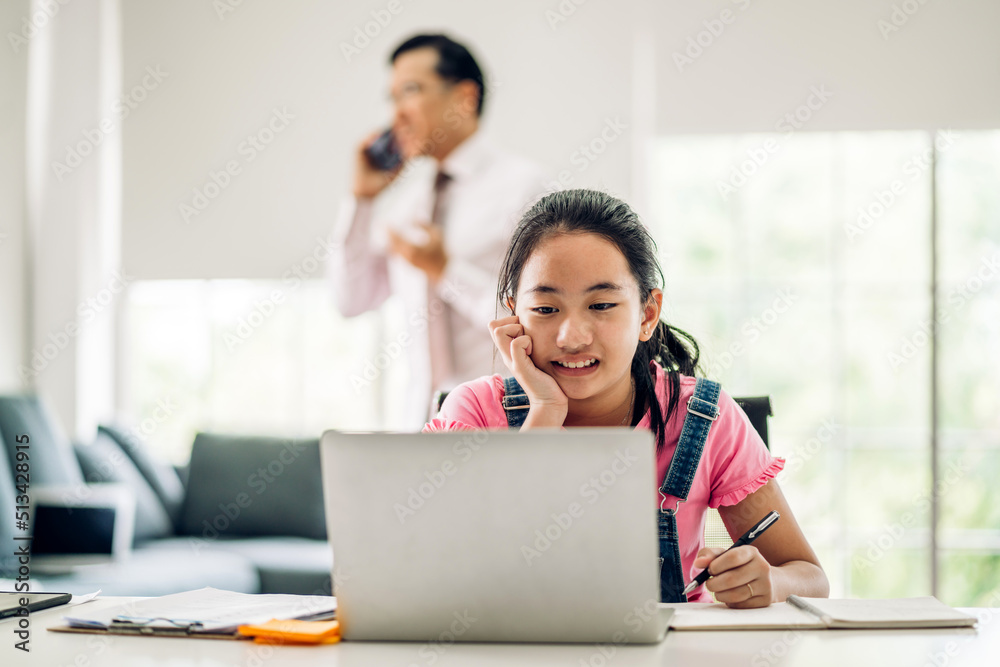 School kid little student girl learning and looking at laptop computer making homework studying knowledge with online education e-learning system.children video conference with teacher tutor at home School kid little student girl learning and looking at laptop computer making homework studying knowledge with online education e-learning system.children video conference with teacher tutor at home