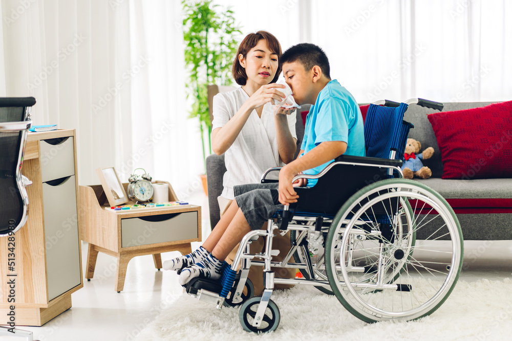 Portrait of enjoy happy love family asian mother playing and carer helping look at disabled son child sitting in wheelchair moments good time at home.disability care concept Portrait of enjoy happy love family asian mother playing and carer helping look at disabled son child sitting in wheelchair moments good time at home.disability care concept